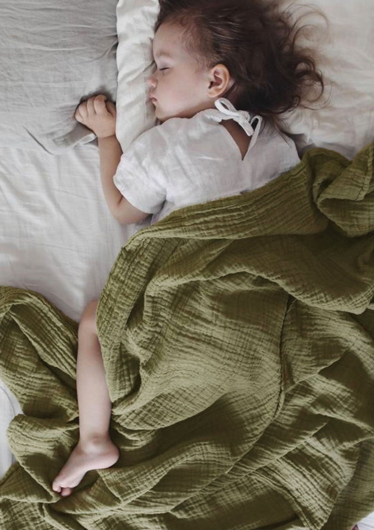 Schlafendes Kleinkind unter NOOSHI Decke in grüner Farbe