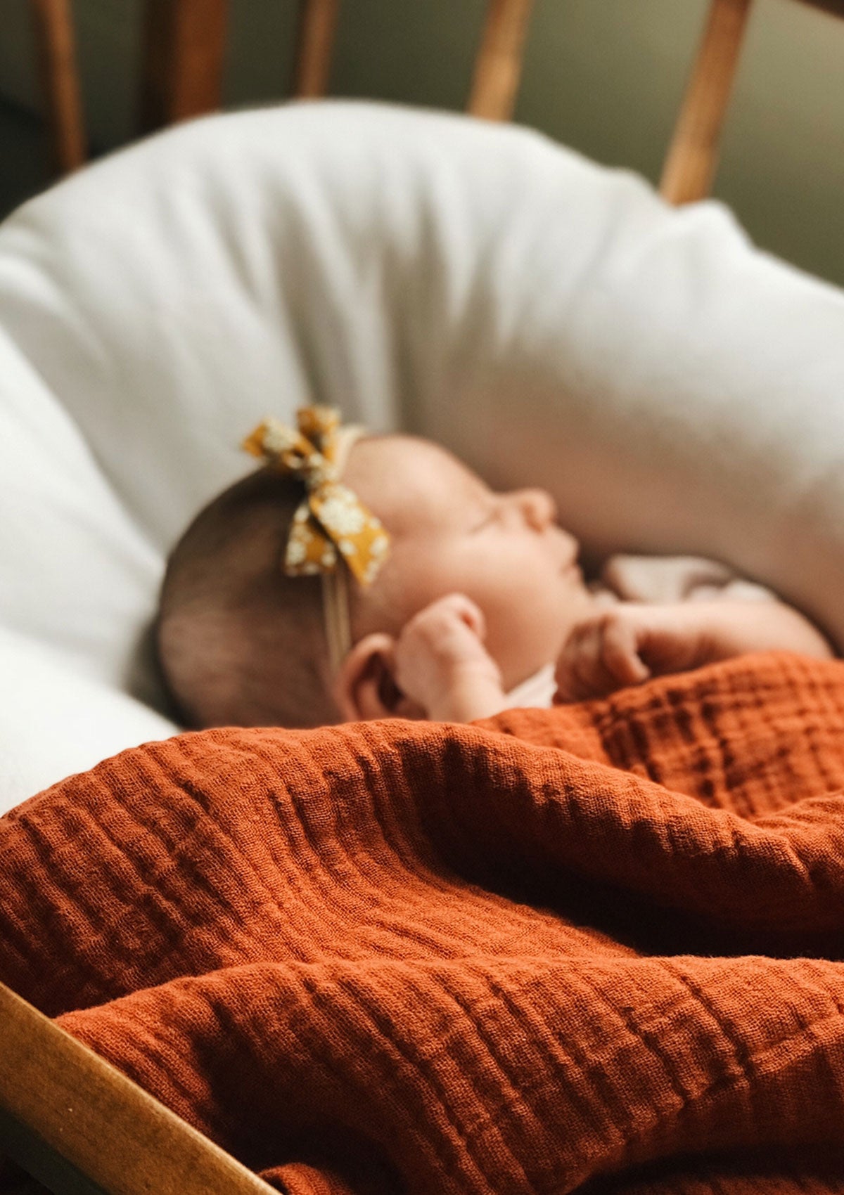 Baby in Bettchen mit Petit Stellou NOOSHI Tuck rostrot Farbe Brick