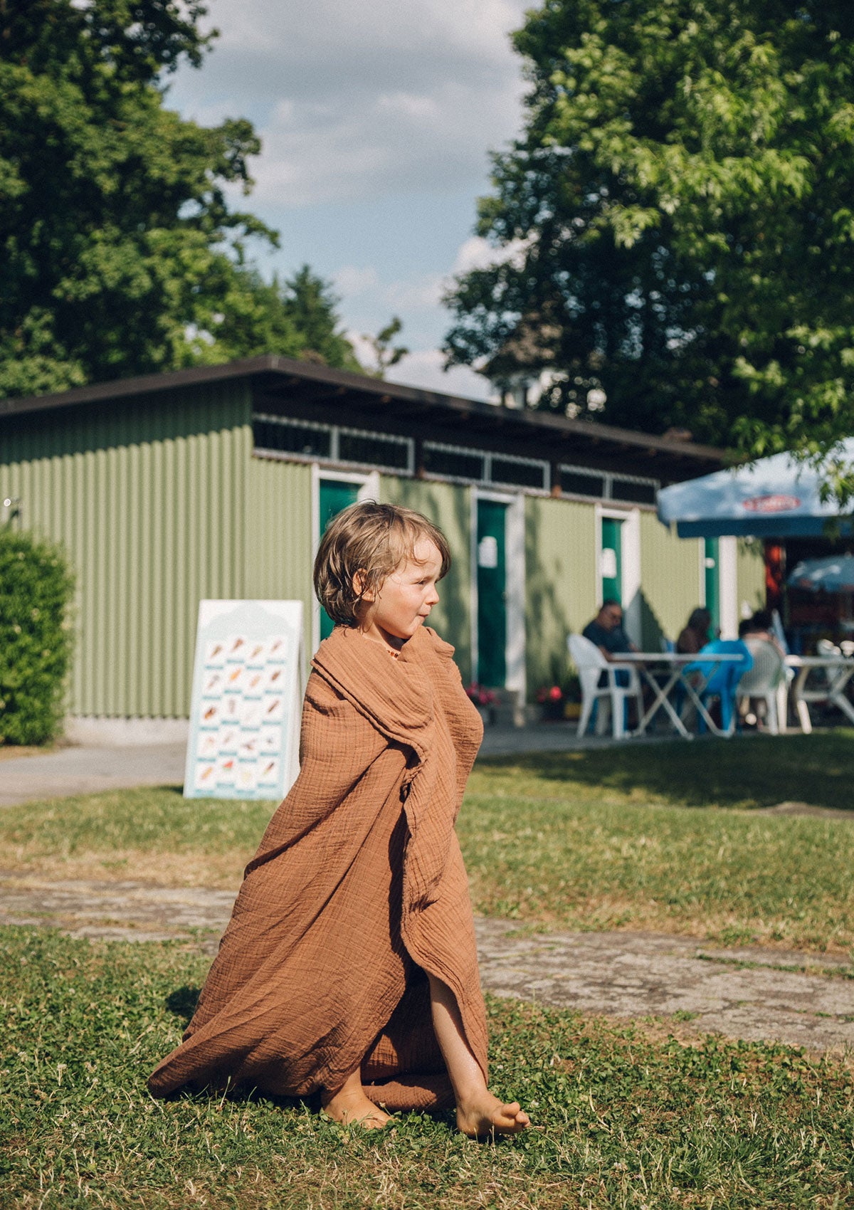 Kleinkind mit Petit Stellou NOOSHI Tuch Hazel braun in der Badi