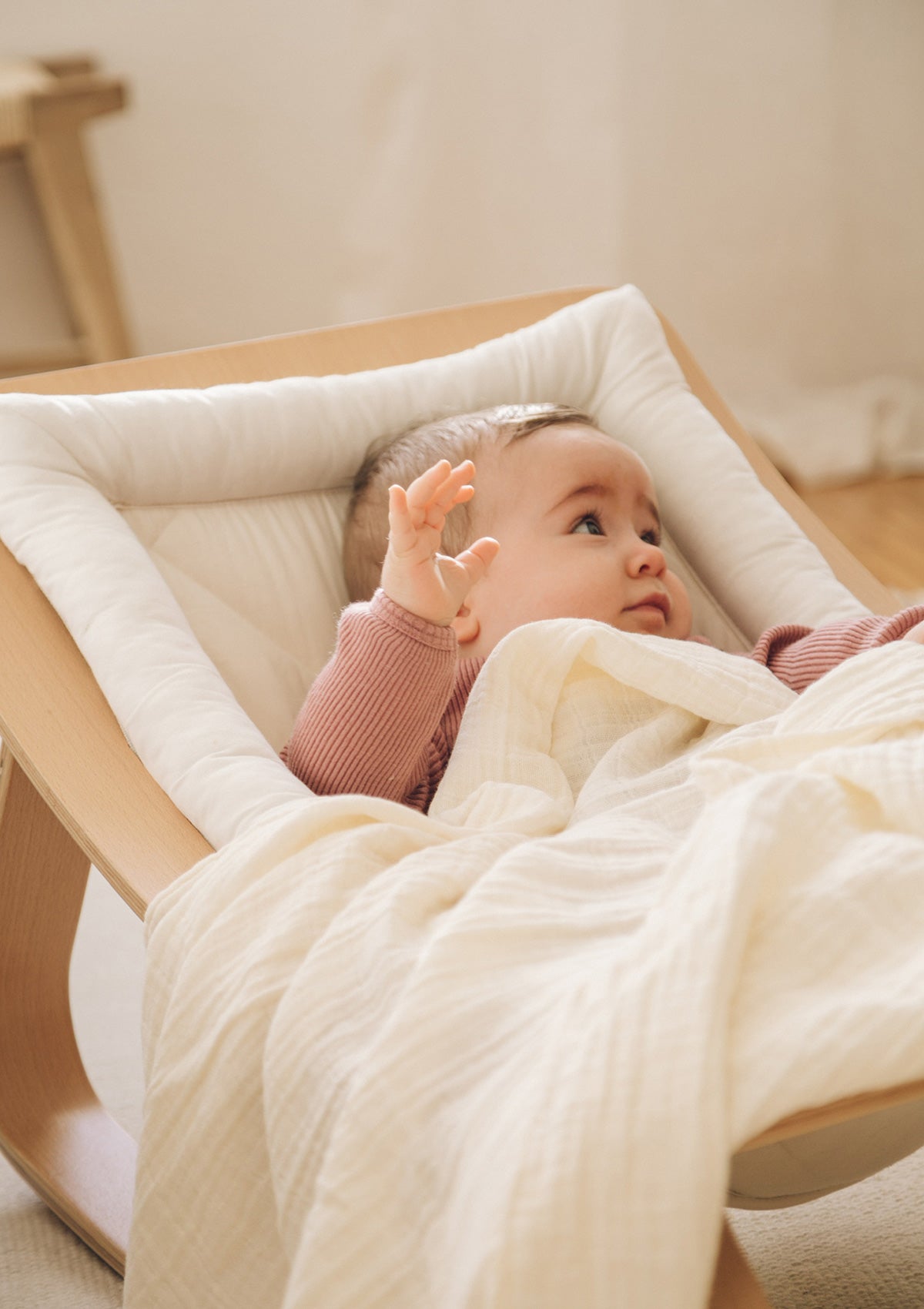 Baby in Wippe mit Musselintuch NOOSHI BLanket Mik weiss