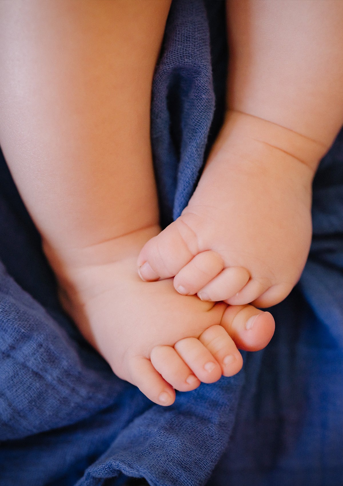 Babyfüsschen auf blauer Musselin-Decke. Petit Stellou NOOSHi BLanket Pool blau