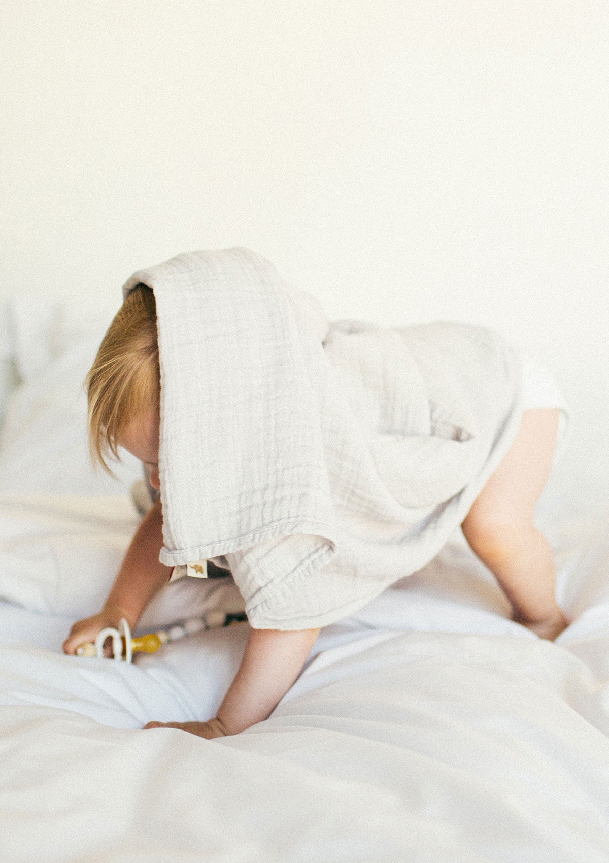 Kleinkind spiel mit Musselintuch. Petit Stellou NOOSHI Cuddle Moonshine hellgrau