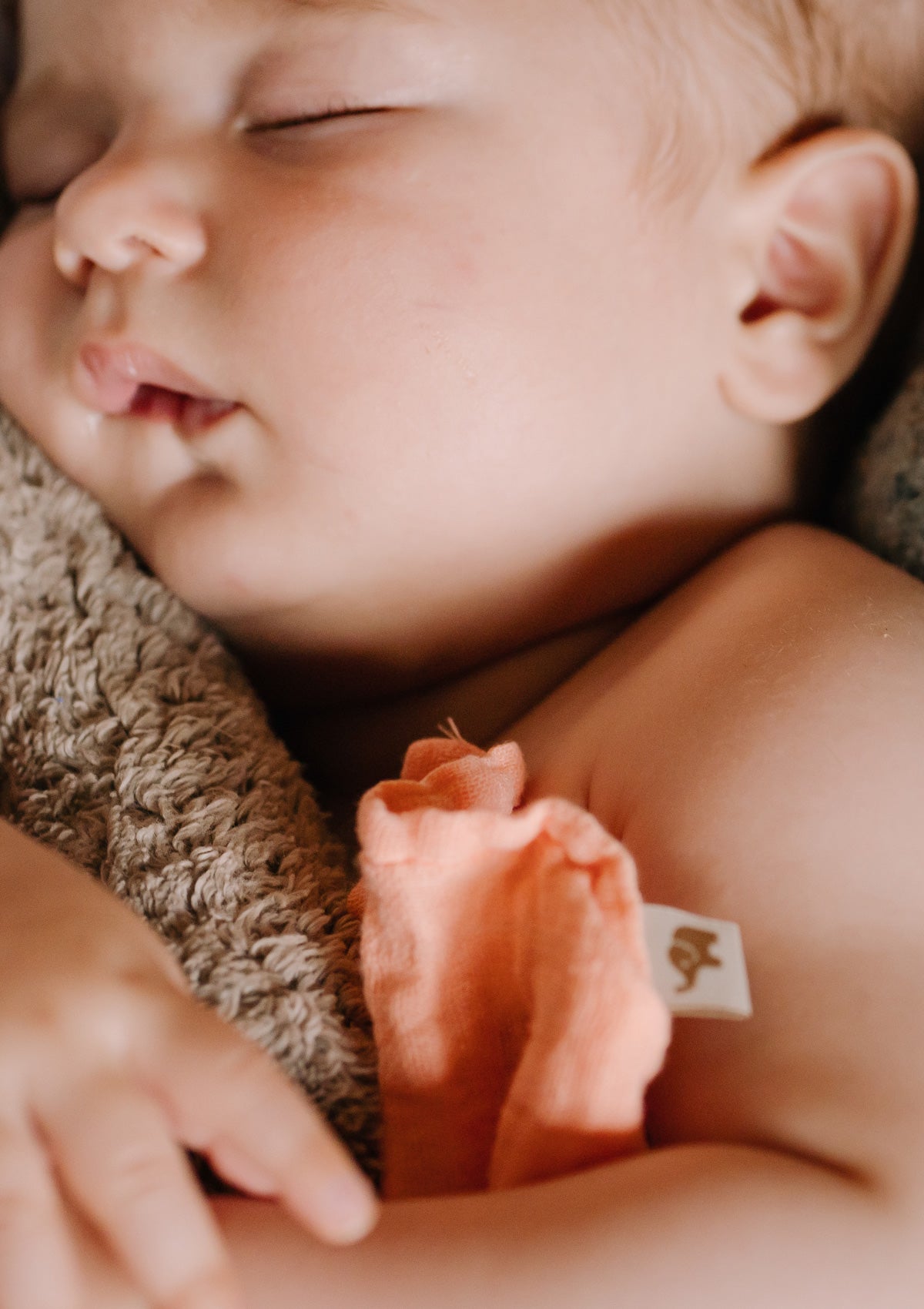 Schlafendes Baby mit Nuschi-Tuch. Petit Stellou NOOSHI Cuddle Peach orange-rosa